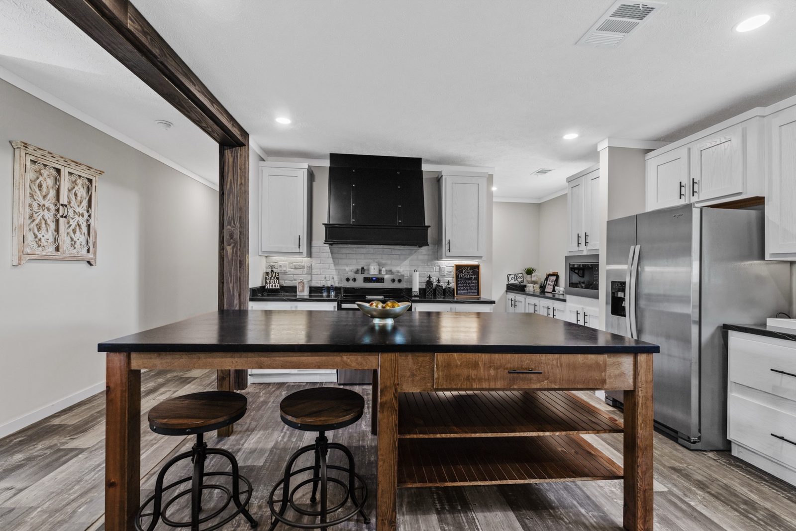 Renovated kitchen with butcher-block island and black range hood
